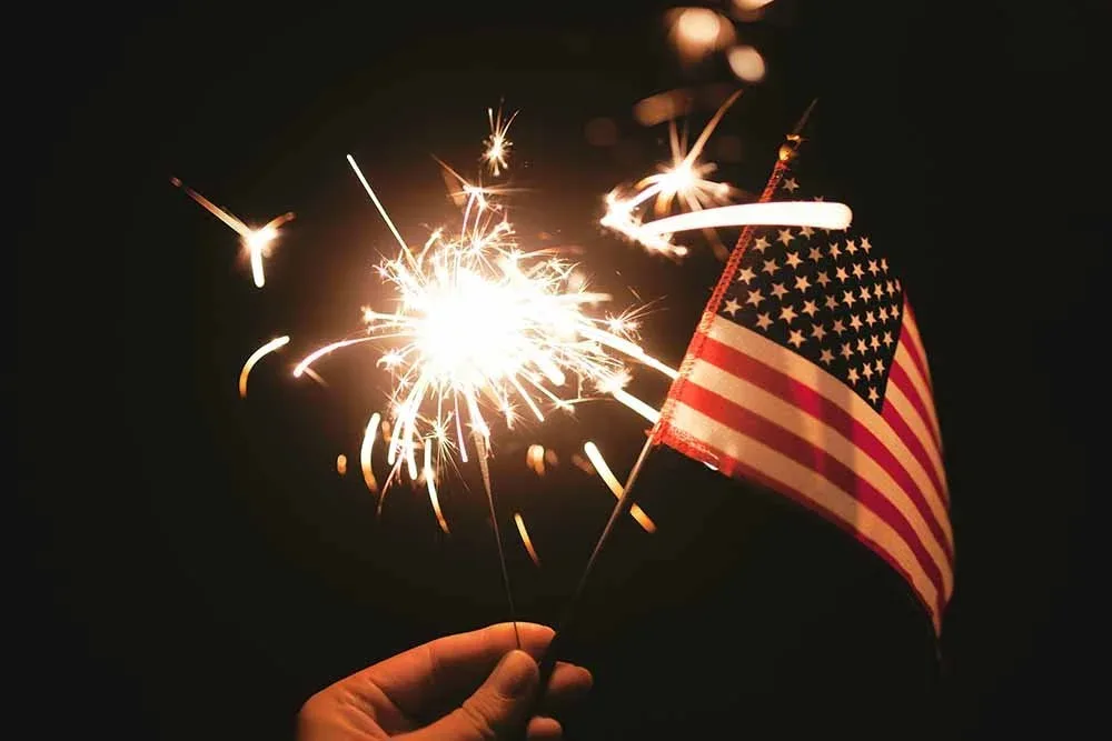 Sparkler and American flag held in hand